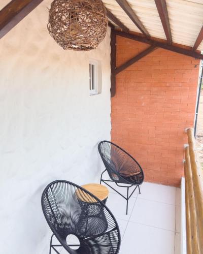 a patio with two chairs and a table and a chandelier at Flats Japaratinga - a 200m da praia com varanda in Japaratinga