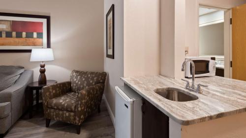 a bathroom with a sink and a chair in a room at Best Western Plus Ambassador Suites in Venice