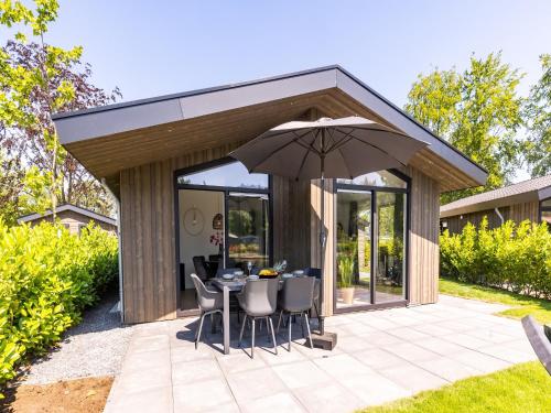 a pavilion with a table and chairs and an umbrella at Chalet by Pond with Sauna in Veldhoven