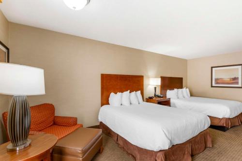 a hotel room with two beds and a chair at Best Western Cotton Tree Inn in Rawlins