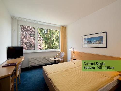 ein Hotelzimmer mit einem Bett, einem Schreibtisch und einem Computer in der Unterkunft Hotel Restaurant Florida in Studen