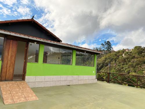 ein grünes Haus mit Blick auf einen Berg in der Unterkunft Pousada Paraíso in Lavras Novas