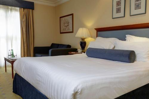 a hotel room with a large white bed and a chair at Manor Hotel Solihull, BW Signature Collection in Bickenhill