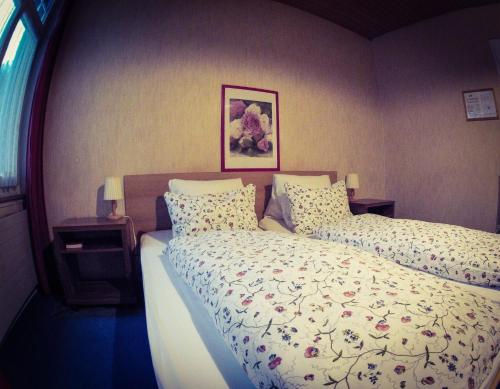 a bedroom with two beds and a picture on the wall at Alpina Hotel in Interlaken