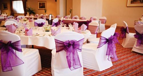 a group of tables with white chairs with purple bows at Best Western Frodsham Forest Hills Hotel in Frodsham