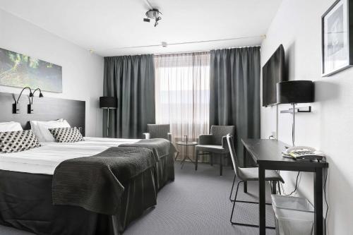 a hotel room with a bed and a table and chairs at Best Western Plus Grand Hotel Elektra in Ludvika