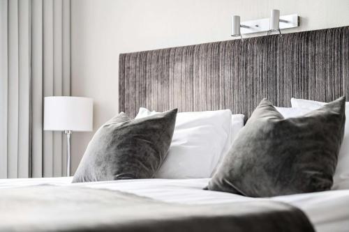 a bedroom with a bed with pillows and a headboard at Best Western Plus Grand Hotel Elektra in Ludvika