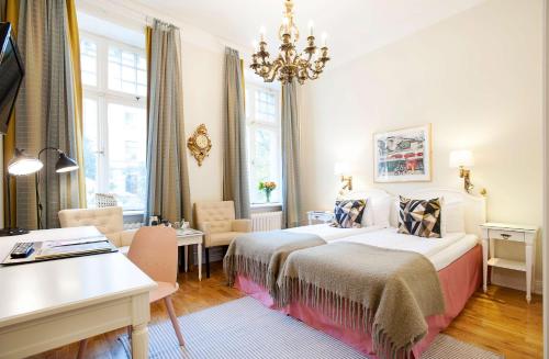 a hotel room with two beds and a desk at Hotel Kung Carl, WorldHotels Crafted in Stockholm