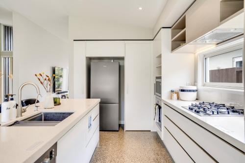 a kitchen with white counters and a stainless steel refrigerator at The Solitude - Comfort at its Best by Carmichael Reserve in Tauranga in Tauranga