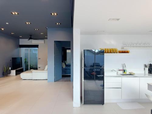 a kitchen with white cabinets and a living room at Contemporary 3bd Safari Pool Villa Near Nai Yang Beach in Ban Bo Han