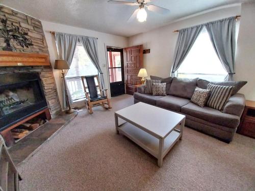 un soggiorno con divano e camino di Valley Condo 101 Creekside - End Unit - Wi-Fi - Hot Tub - Fireplace - Washer - Dryer - Playground a Red River