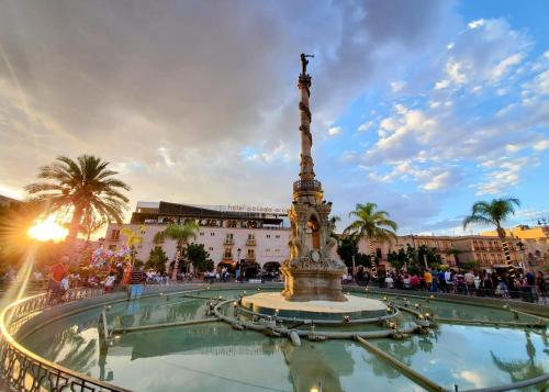 a fountain in the middle of a square with a statue at Hotel Posada Arcos in San Juan de los Lagos