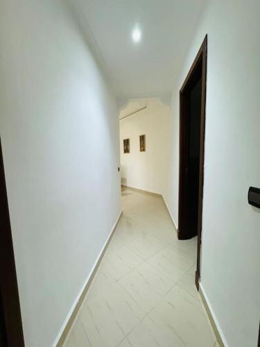 a hallway with a white wall and a door at appartement de vacances achakar plage & piscine & wifi in Tangier
