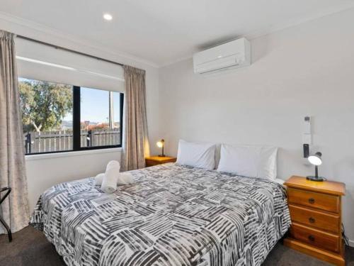 a bedroom with a bed and a large window at MiddleIsland-FREE & FAST wifi NETFLIX & aircon in Taupo