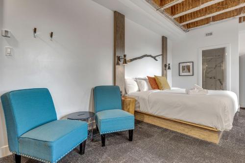 a bedroom with a bed and two blue chairs at La Sainte Paix in Quebec City
