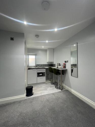 a white kitchen with a table and a counter at Cozy Studio Flat Romford, London in Romford
