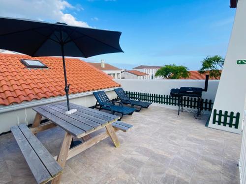 a patio with two chairs and an umbrella on a roof at Alojamento CANTO NA RELVA in Ponta Delgada