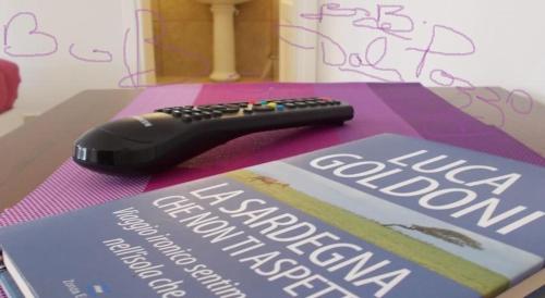 a remote control sitting on top of a book at casa di campagna dal pozzo in Sorso