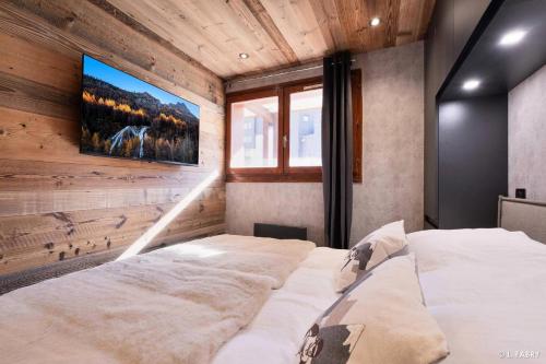 - une chambre avec 2 lits et une télévision murale dans l'établissement Résidence Hameau Du Borsat 1& 2 - Appartement 6 personnes - Au pied des pistes MAE-2734, à Tignes