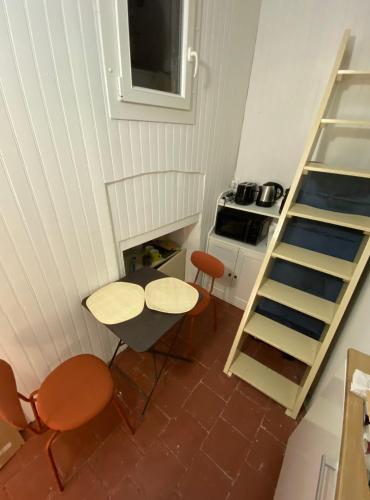 une cuisine avec une table, des chaises et une échelle dans l'établissement Le petit change, à Avignon