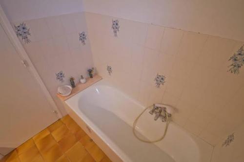 La salle de bains est pourvue d'une baignoire avec des fleurs bleues sur le mur. dans l'établissement Lugaro, à Calvi