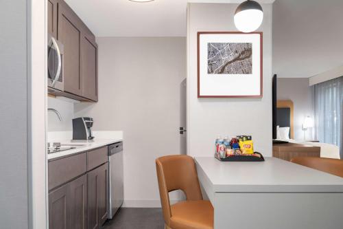 a kitchen with a white counter and a table and chairs at Homewood Suites by Hilton Detroit-Troy in Birmingham