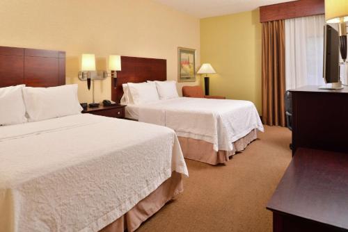a hotel room with two beds and a flat screen tv at Hampton Inn Staunton in Staunton