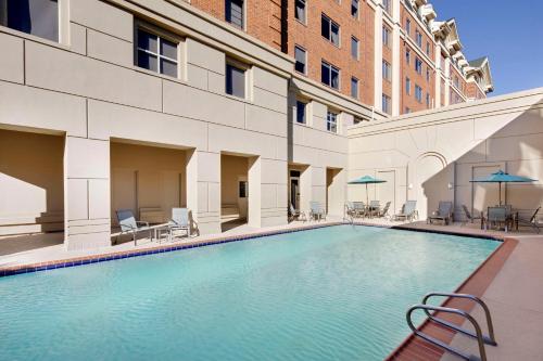 a swimming pool in a building with chairs and umbrellas at DoubleTree by Hilton Atlanta/Roswell - Alpharetta Area in Roswell