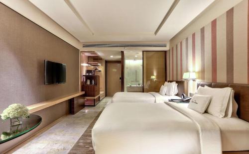 a hotel room with two beds and a television at DoubleTree by Hilton Sukhumvit Bangkok in Bangkok