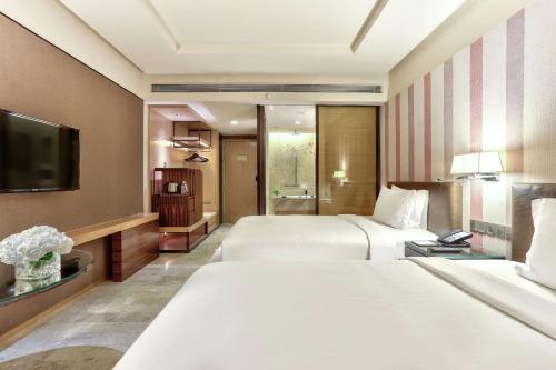 a hotel room with two beds and a television at DoubleTree by Hilton Sukhumvit Bangkok in Bangkok