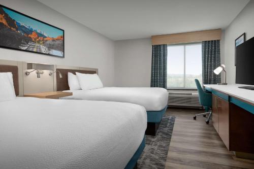 a hotel room with two beds and a desk at Hilton Garden Inn Colorado Springs North in Colorado Springs