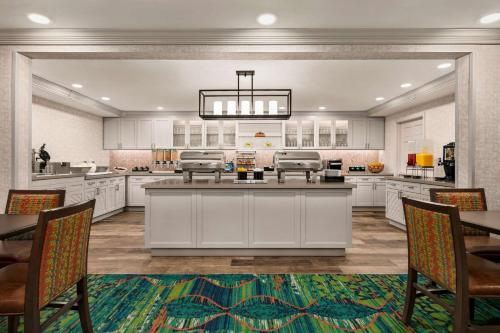 a large kitchen with white cabinets and a table and chairs at Homewood Suites by Hilton Fort Myers in Fort Myers