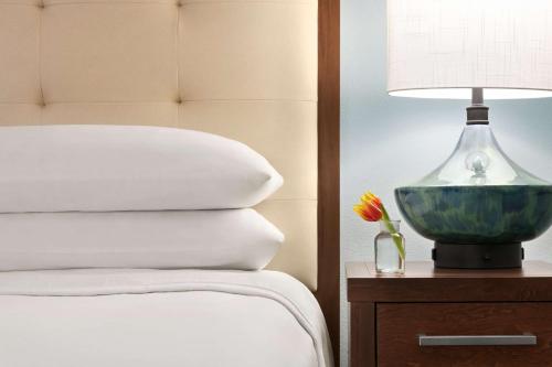a bed with a lamp and a vase with a flower at Homewood Suites by Hilton Fort Myers in Fort Myers