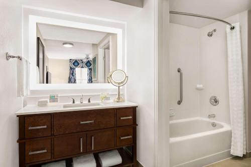 a bathroom with a sink and a tub and a mirror at Homewood Suites by Hilton Fort Myers in Fort Myers