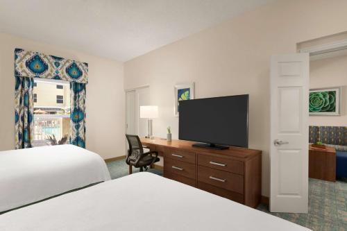 a hotel room with two beds and a flat screen tv at Homewood Suites by Hilton Fort Myers in Fort Myers