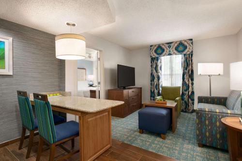a living room with a dining table and a living room with a couch at Homewood Suites by Hilton Fort Myers in Fort Myers