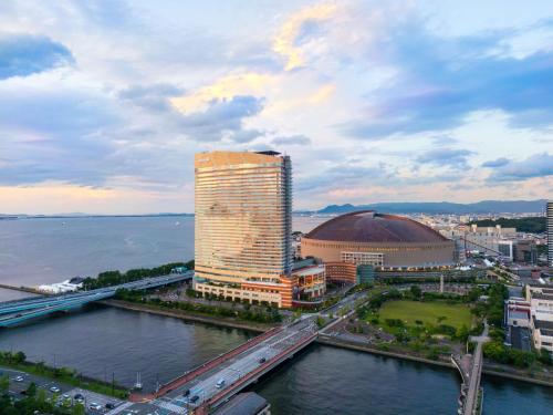 a tall building next to a river with a bridge at Hilton Fukuoka Sea Hawk in Fukuoka