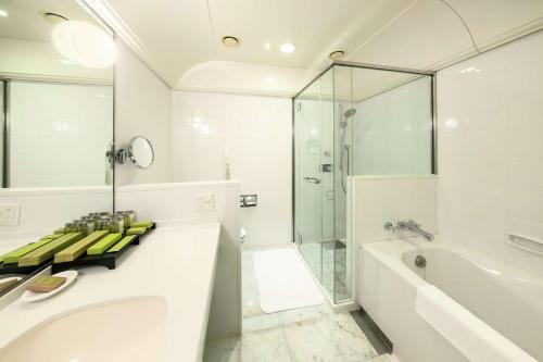 a bathroom with a shower and a tub and a sink at Hilton Fukuoka Sea Hawk in Fukuoka