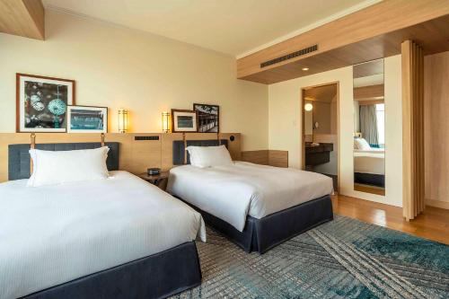 a hotel room with two beds and a bathroom at Hilton Fukuoka Sea Hawk in Fukuoka