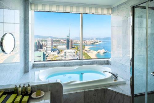 a bathroom with a tub and a large window at Hilton Fukuoka Sea Hawk in Fukuoka