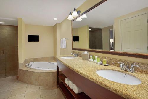 a bathroom with two sinks and a tub and a large mirror at Hilton Jackson in Jackson