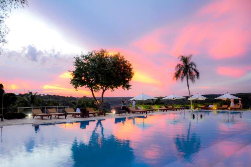 a large swimming pool with a sunset in the background at Panoramic Grand - Iguazú in Puerto Iguazú