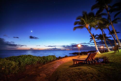 a bench sitting on a path near the ocean at night at Hilton Waikoloa Village in Waikoloa