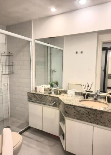 a bathroom with a sink and a toilet and a mirror at Super Comfort Flats lll - WTC - com Estacionamento in Sao Paulo