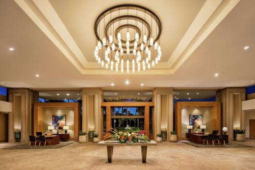 a lobby with a large chandelier and a table with flowers at Hilton Waikoloa Village in Waikoloa