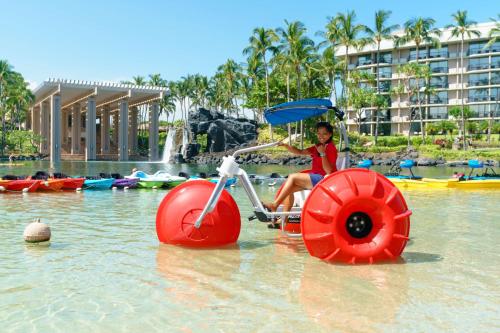 a young girl sitting on a bike in the water at Hilton Waikoloa Village in Waikoloa