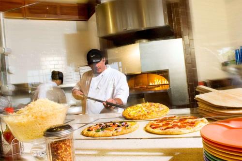 a man in a kitchen preparing pizzas in a kitchen at Hilton Waikoloa Village in Waikoloa
