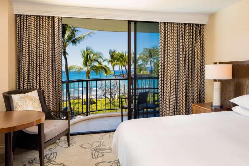 a bedroom with a bed and a view of the ocean at Hilton Waikoloa Village in Waikoloa