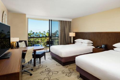 a hotel room with two beds and a desk at Hilton Waikoloa Village in Waikoloa