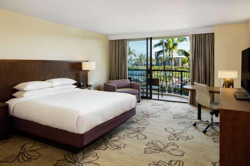 a hotel room with a bed and a desk and a balcony at Hilton Waikoloa Village in Waikoloa
